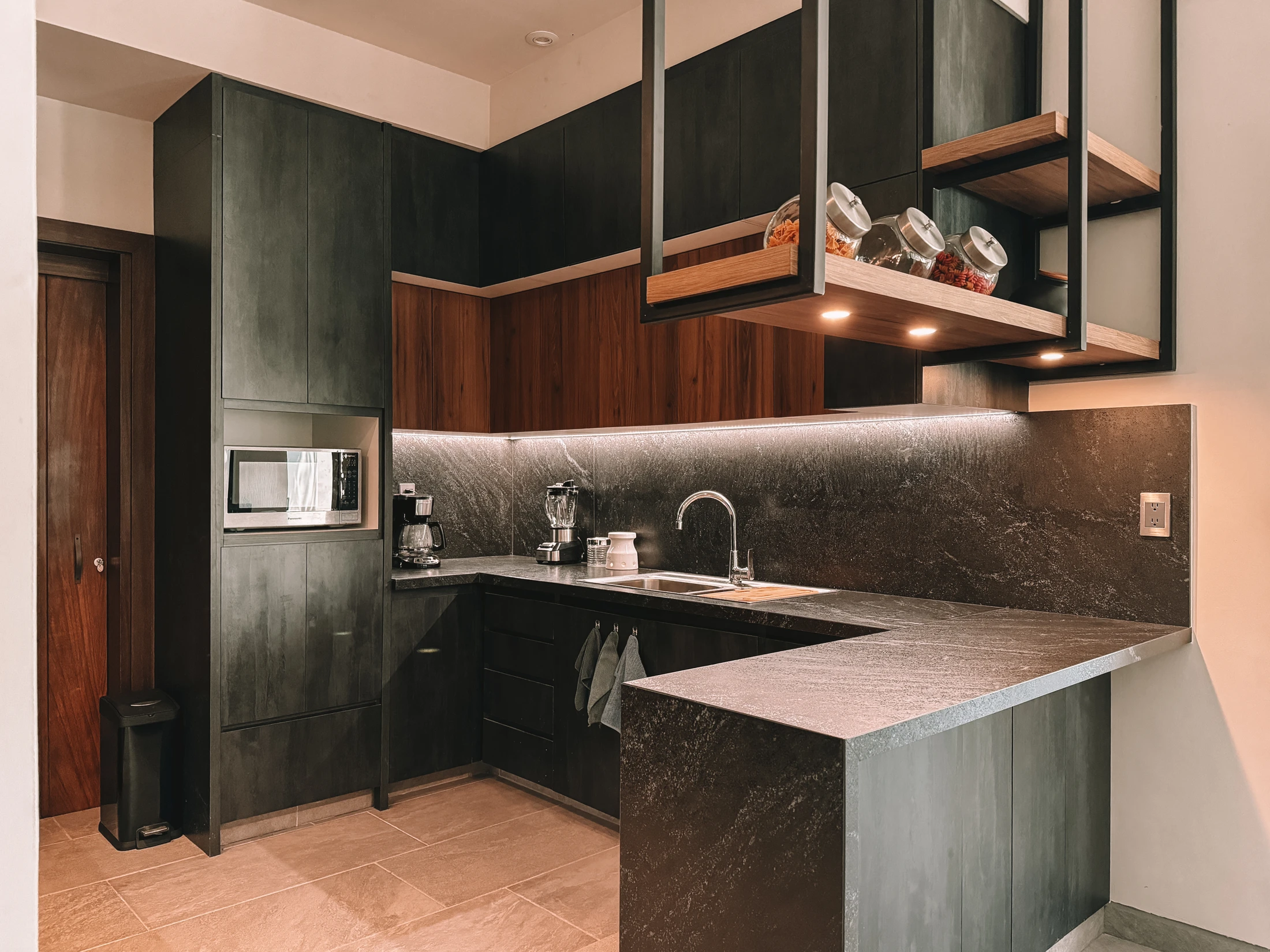Cocina con mobiliario oscuro, piedra y madera