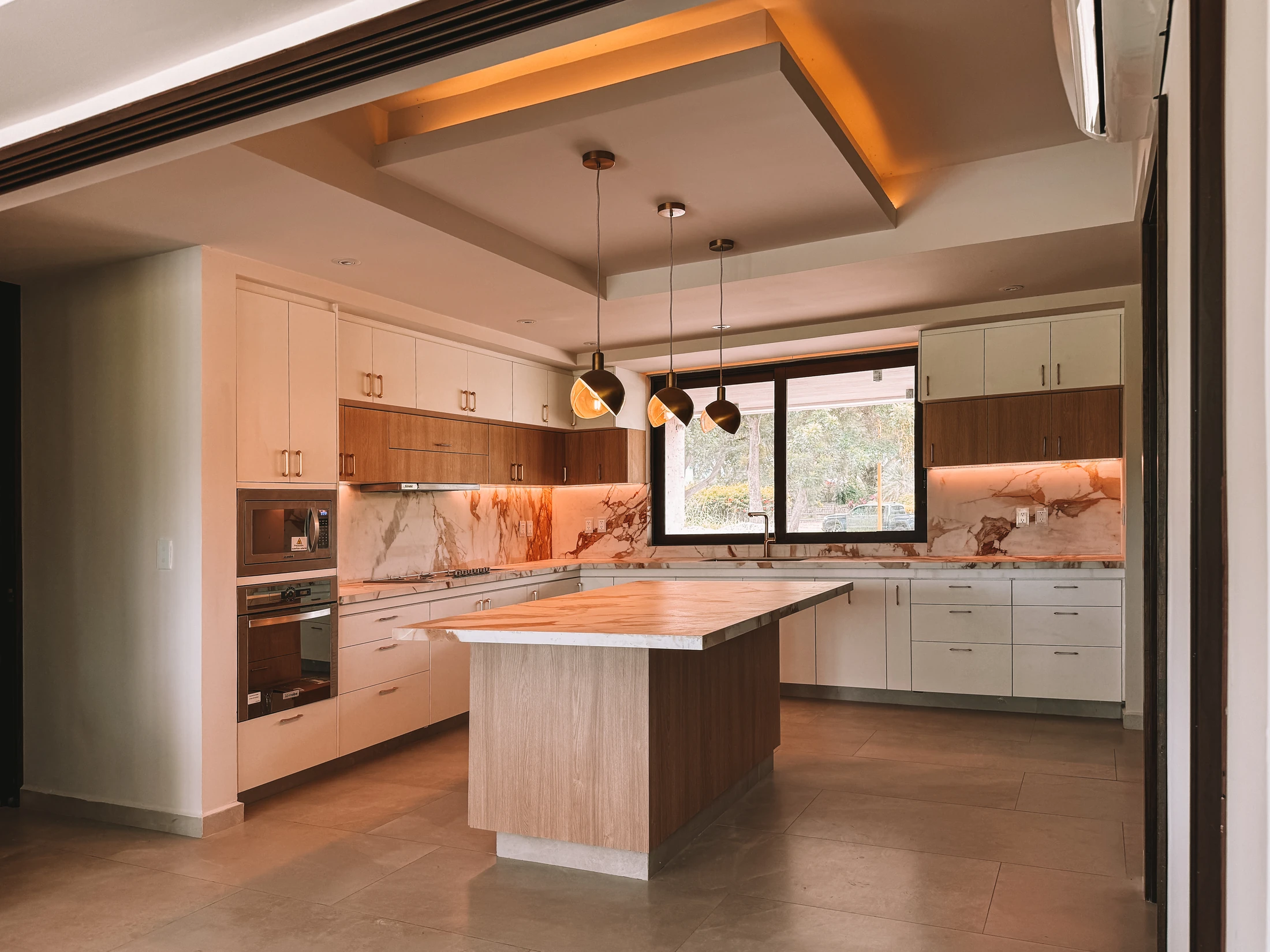 Cocina diseñada por DORIA con isla, cubiertas de piedra y mobiliario en madera